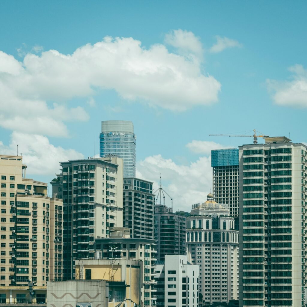A vibrant cityscape showcasing modern skyscrapers under a blue sky with clouds.